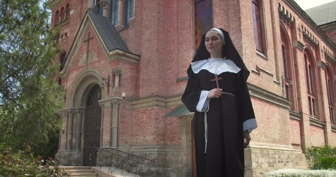 Young nun praying outdoors near monastery