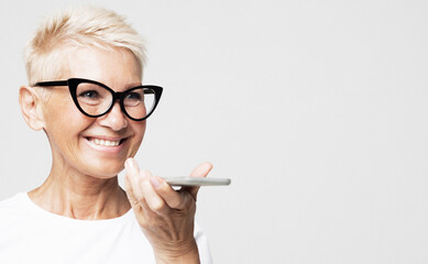 Smiling elderly woman recording voice message on phone close up, old age, technology and people concept