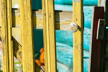 Yellow wooden fence, wicket gate with white vintage fittings