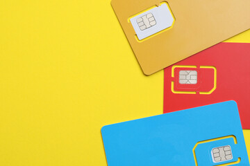 Different SIM cards on yellow background, flat lay. Space for text