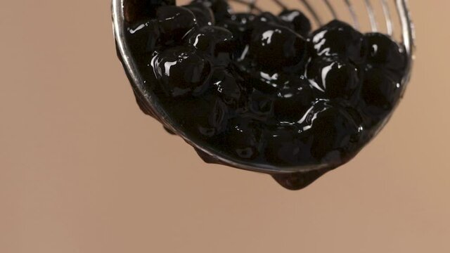  Succulent Black Tapioca Pearls Falling from Steel Skimmer, Macro Shot