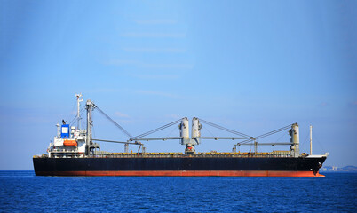 Fototapeta premium Container ship carrying container box in import export with quay crane, Global business cargo freight shipping commercial trade logistic and transportation oversea worldwide by container vessel.