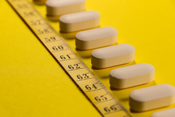 Pills With Measuring Tape Diagonal Line On Yellow