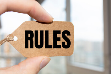 Cropped view of hands holding wooden block with RULES lettering on work table. Top view