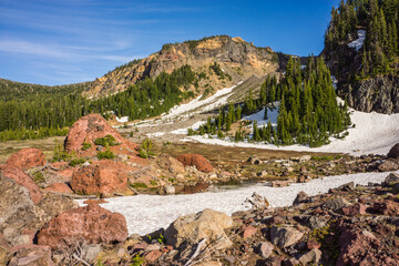 Fototapeta na wymiar Rocky volcanic mountain landscape with colored rocks, trees, and a blue sky.