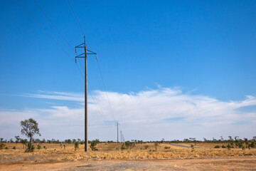 Power poles disappearing into savannah landscape at Corfield in Queensland, Australia