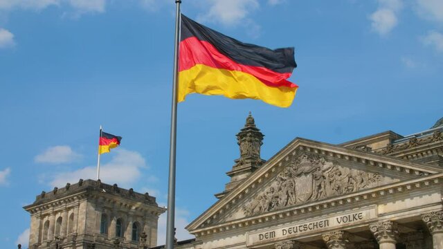 Reichstag Bundestag Berlin Deutschland Germany with german flag UHD and clouds on blue sky
