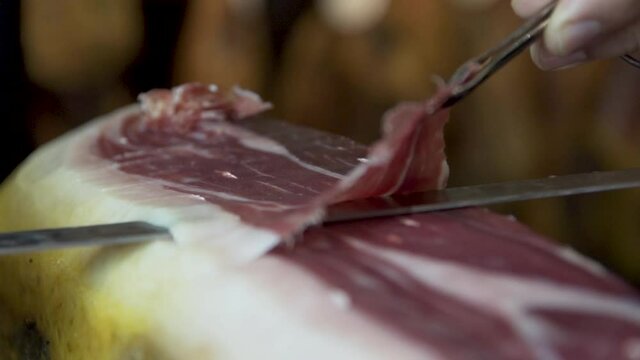 CloseUp of carefully sliced Serrano ham, gently laid on plate to serve
