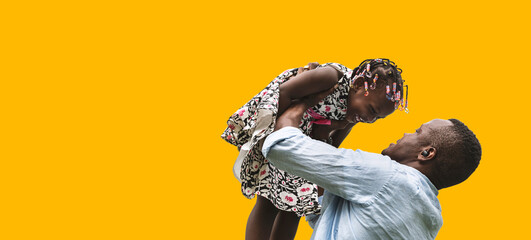 Father tease daughter by lifting her daughter isolated on yellow backgrounds, African family.	