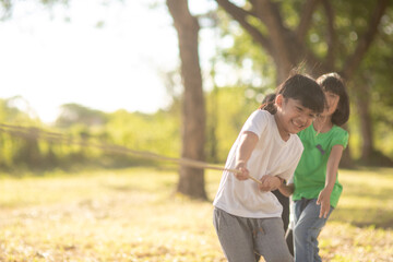 Children playing tug of war at the park on sunsut