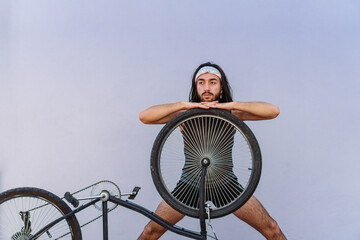 young latino hispanic long haired man with his upside down bike posing on top of the rim. reframed,...