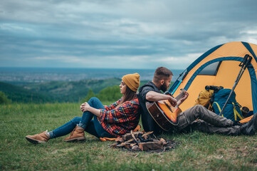 Couple playing guitar and having a romantic date while spending a time in the nature