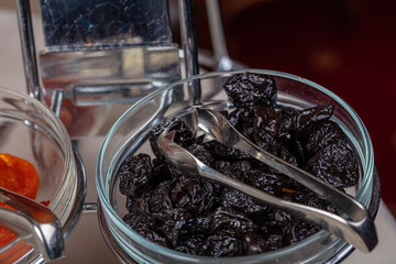 Prunes, dried fruits in a small glass plate.