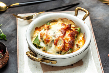 Portion of hot spinach crepes or pancakes with chicken and mushrooms baked with cheese. Restaurant menu, dieting, cookbook recipe. top view