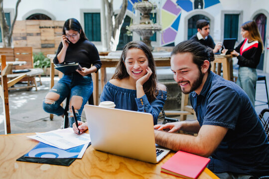 Smiling hispanic college students sitting while taking online class in Latin America