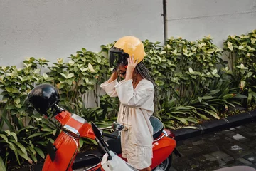 Raamstickers Woman with helmet and scooter outside in bali © Fxquadro