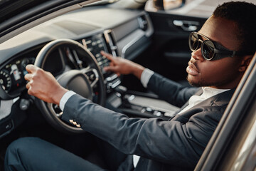 Fototapeta na wymiar Stylish black businessman inside of car holding wheel