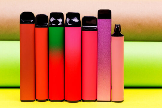 Disposable single pink e-cigarettes with saline nicotine. Pod systems in a row of different colors. Devices for quitting smoking. Red, yellow, green, pink and black. conceptual fashion photo