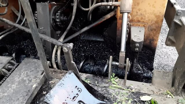 A paver finisher, asphalt finisher, or paving machine placing a layer of asphalt (damar, damar road) during a repaving construction project