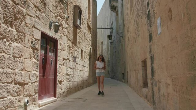 Lonely Female Tourist Walking in Narrow Street of Mdina, Malta. Medieval Town With Limestone Walls, Tourist Attraction on Summer Day