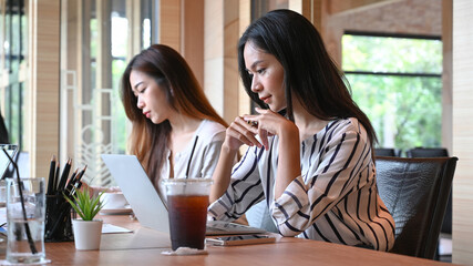 Two young woman designer working together in modern creative office.