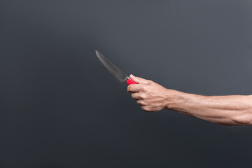 Rusty old knife with a red handle in the male hand. With space for an inscription. Kitchen meat knife in the hand isolated over grey background. Chief steel knife. Killer man holding knife in hand