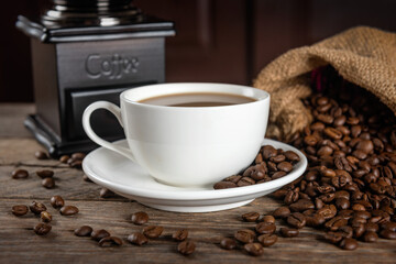 Cup of coffee and heap of beans on a wooden table