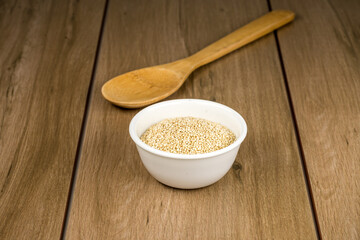 Tazón de cerámica blanca con semilla de quinoa sobre madera
