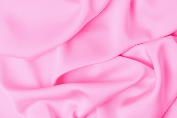 Folds on pink silk fabric close-up, texture and background.