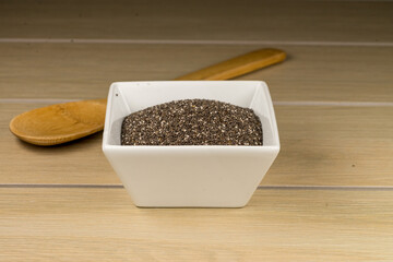 Tazón de cerámica blanca con semilla de chia sobre madera