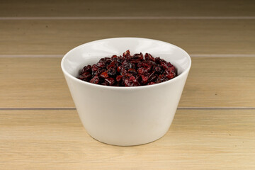 Tazón de cerámica blanca con arándanos secos sobre madera