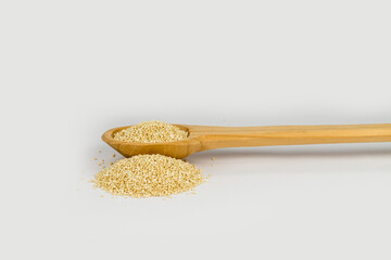 Cuchara de madera con semilla de quinoa y fondo blanco