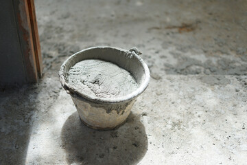 mixing mortar in a bucket put on a dirty floor prepare for plastering,soft focus