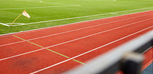 Red treadmill on sport field. Landscape of soccer field with green grass and running track