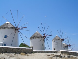  four of the famous white-washed mykonos windmills on the aegean sea on a sunny day on  mykonos island,  greece