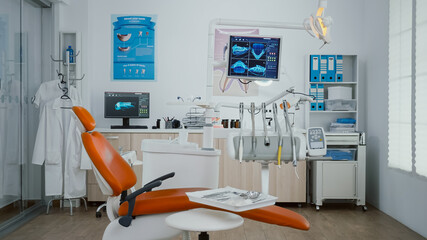 Zoom in shoot of stomatology orthodontist office room with tooth xray images on monitor ready for dental surgery. Orthodontic dentistry workplace equipped with dentist chiar and teeth instruments