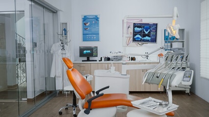 Empty orthodontic stomatology office prepared for teeth treatment after medical dental diagnosis. Doctor cabinet equipped with tooth instruments for oral care. Dentistry xray images on monitor