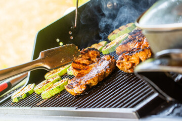 Modern gas garden grill. Preparing Juicy chicken steaks and grilled zucchini slices