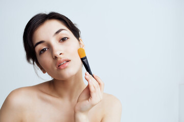 woman with bare shoulders makeup brush cosmetics skin care close-up