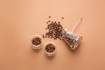 Cups and cezve with coffee beans on color background