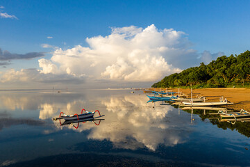 Dramatic sunrise over Sanur beach and traditional fisher man balinese boats in Bali, Indonesia