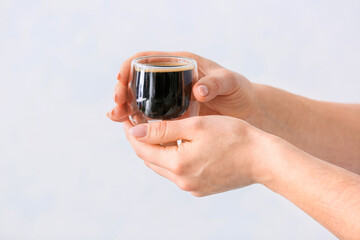 Woman with cup of turkish coffee on light background