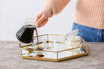 Woman pouring turkish coffee from cezve into cup in kitchen