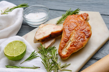 Board with tasty chicken fillet on dark wooden background