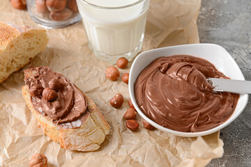 Bowl with tasty chocolate paste and hazelnuts on parchment