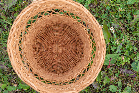 A Small Empty Wicker Basket Standing On The Grass In The Middle Of A Forest Park. The Concept Of Picking Fruits And Vegetables At The End Of Summer. View From Above