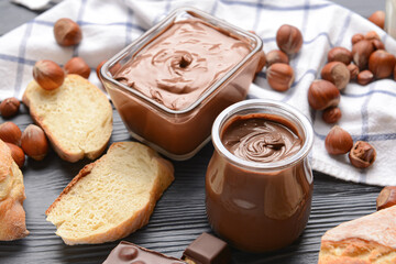 Composition with tasty chocolate paste and hazelnuts on dark background