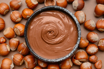 Bowl with tasty chocolate paste and hazelnuts on color background