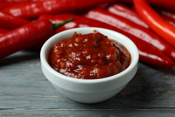 Red chili peppers and sauce on gray wooden background