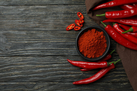 Red chili peppers and powder on rustic wooden background